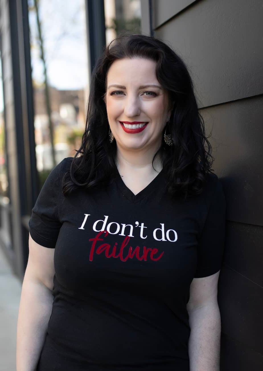 Monica, a white woman with dark hair, wearing a black tshirt that says  "I don't do failure"